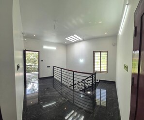 A clean, modern interior with a marble floor, a staircase with a metal railing, and a door with a window. - Serene Green Retreat Pothencode (Nedumangad)