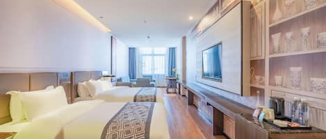 Quarto de hotel com duas camas, televisão, mesa com cafeteira e prateleira com objetos decorativos.