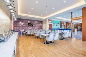 A modern dining area with a long counter, multiple tables, and chairs. - Gem Anqing Wangjiang County Central Mall Fengqi Road Hotel (Anqing)