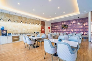 Un moderno comedor con varias mesas y sillas, una encimera de cocina y una pared con un mural de la ciudad.