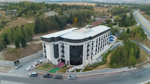 Un edifici modern amb façana corbada, zona d'aparcament i carretera propera.