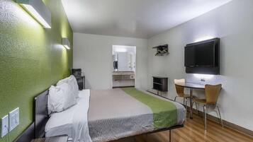 Ein Hotelzimmer mit Bett, Schreibtisch, Stuhl, Fernseher und Spiegel.