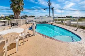 A swimming pool with a tiled edge, surrounded by a white fence, and a palm tree in the background. - 1 King Bed | Non-Smoking, Micfridge (San Marcos)