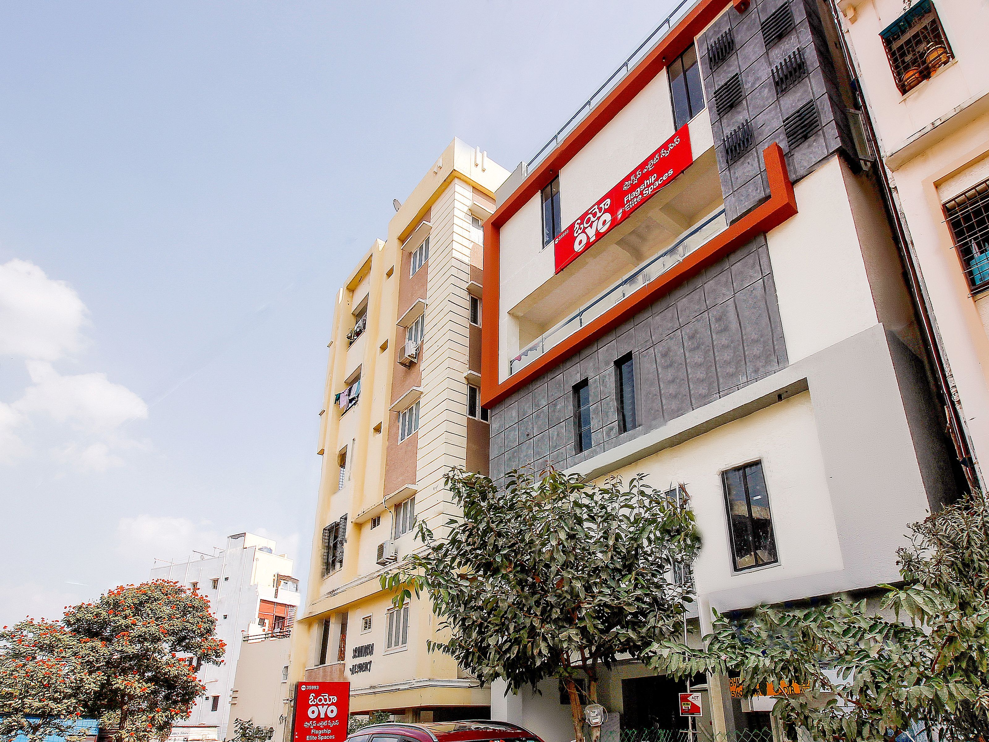 Um edifício de vários andares com varandas e uma placa vermelha que indica 'Flagship Elite Spaces'.