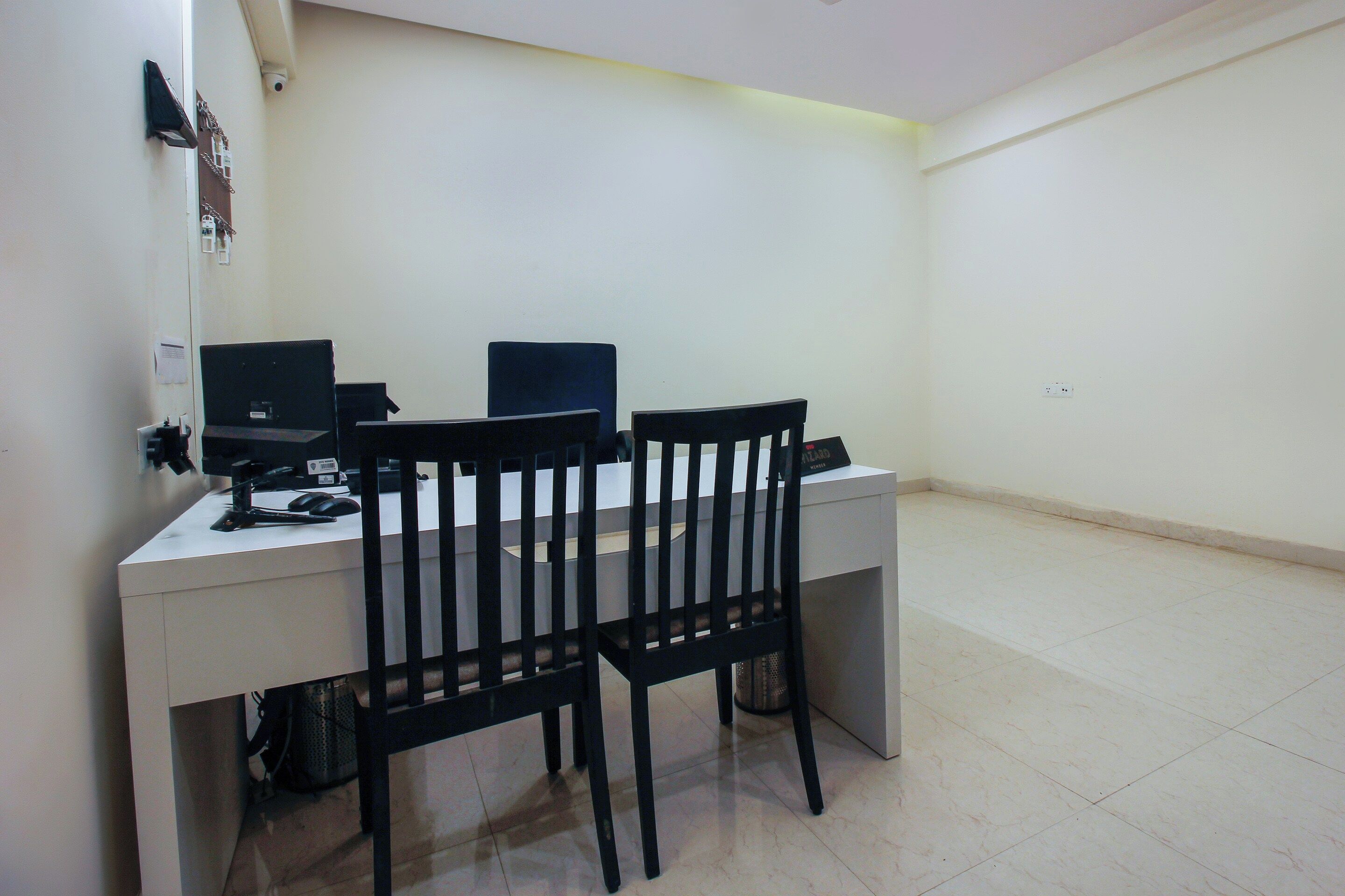 A small office space with a desk, two computer monitors, a chair, and a trash bin.