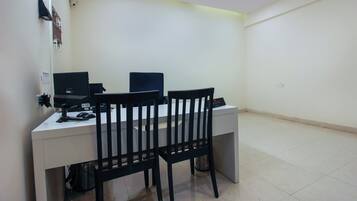 A small office space with a desk, two computer monitors, a chair, and a trash bin.