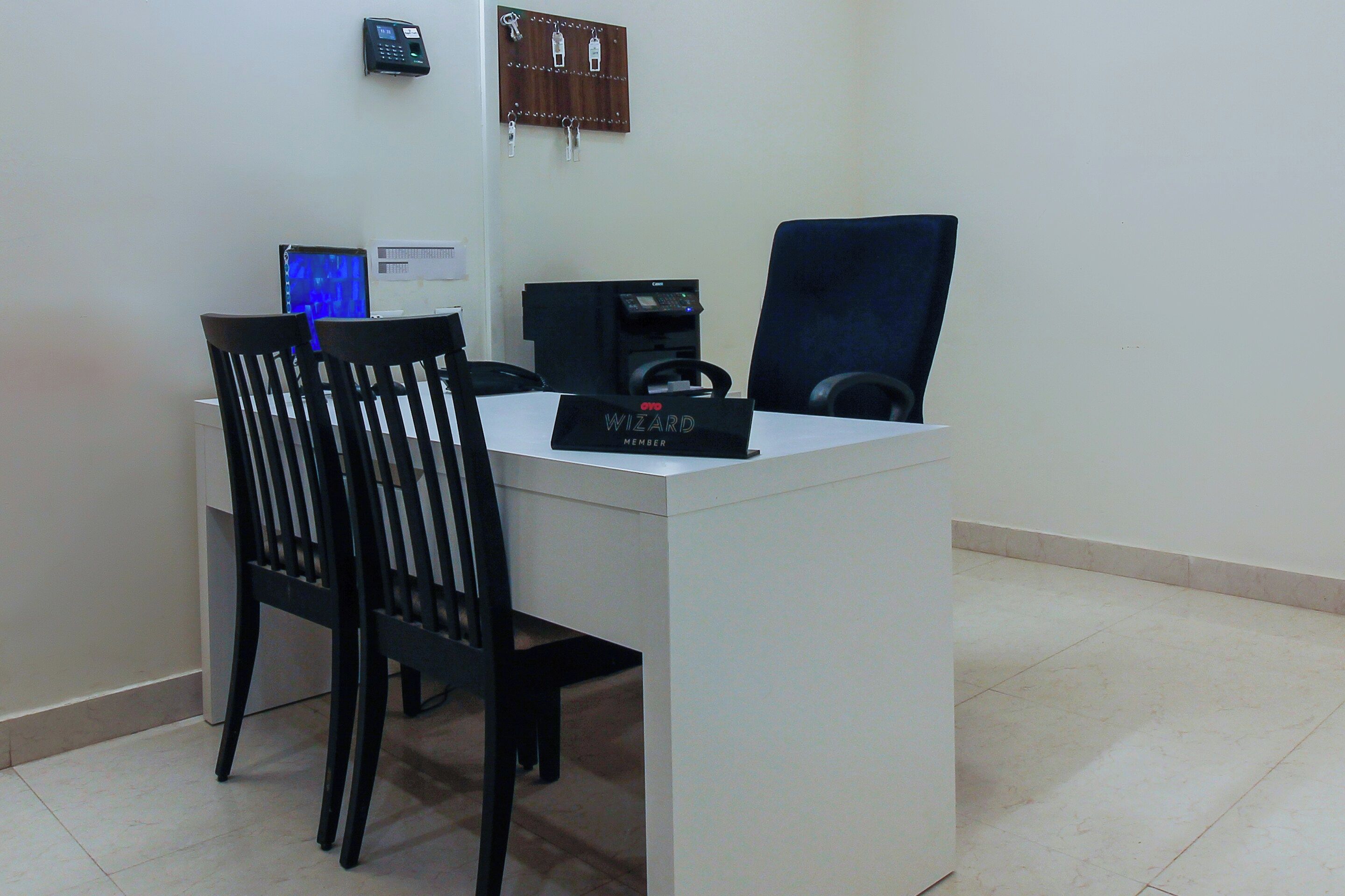 A reception desk with a computer, a coffee machine, and a chair.
