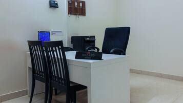 A reception desk with a computer, a coffee machine, and a chair.