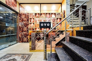 A hotel entrance with a marble wall, a staircase, and a sign that reads 'OYO'. - Hotel O Gold Wood (Amritsar)