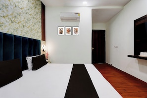 A hotel room with a bed, a wall-mounted air conditioner, and three framed leaf designs. - Hotel O Gold Wood (Amritsar)