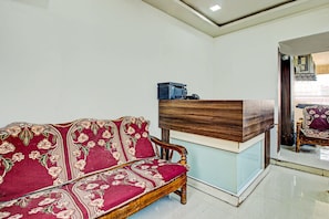 Ein Empfangstisch mit Holzoptik und ein Sofa mit Blumenmuster.
