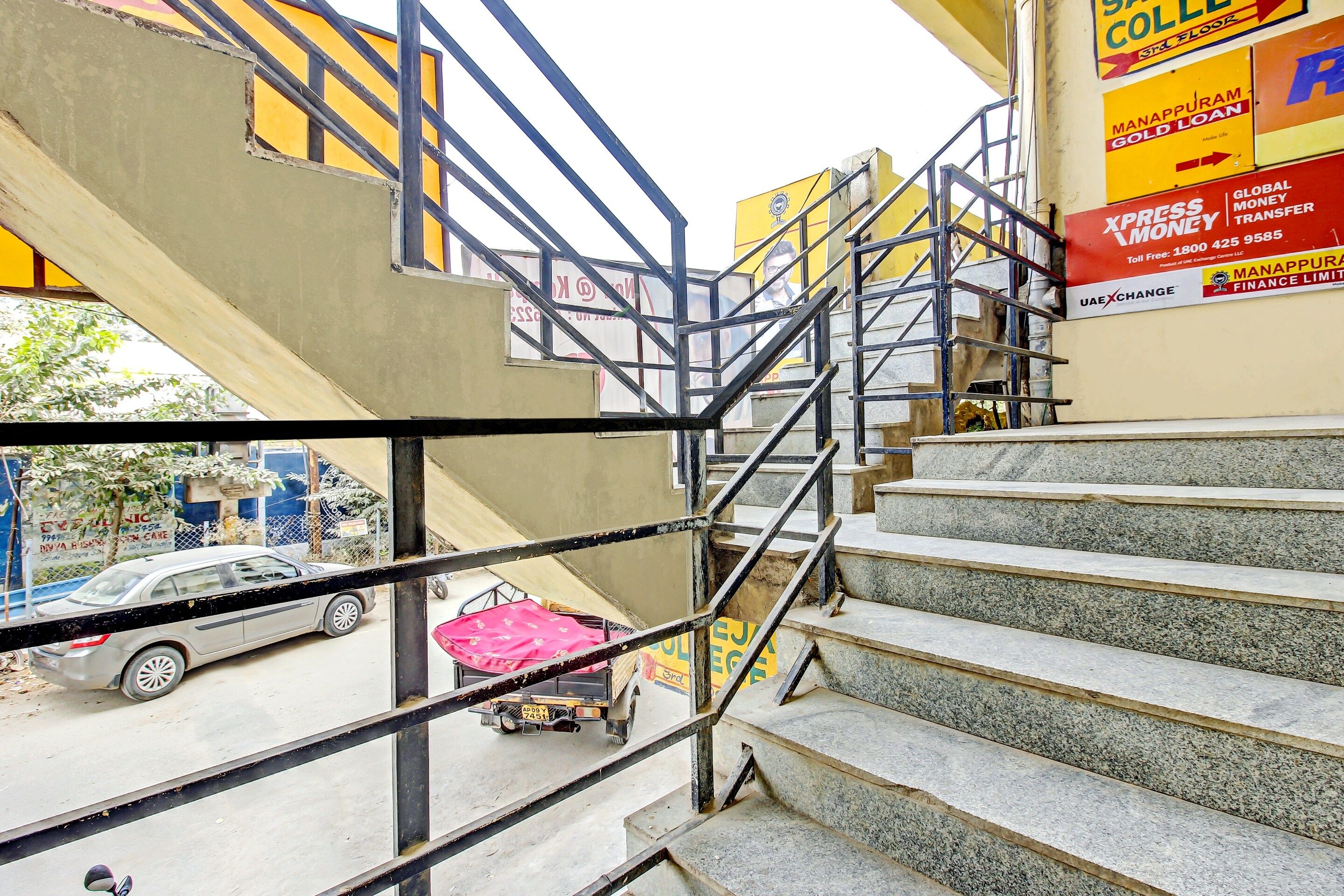 A staircase leading to an upper floor with metal railings and a view of a street below.