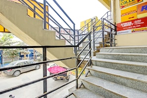 A staircase leading to an upper floor with metal railings and a view of a street below.