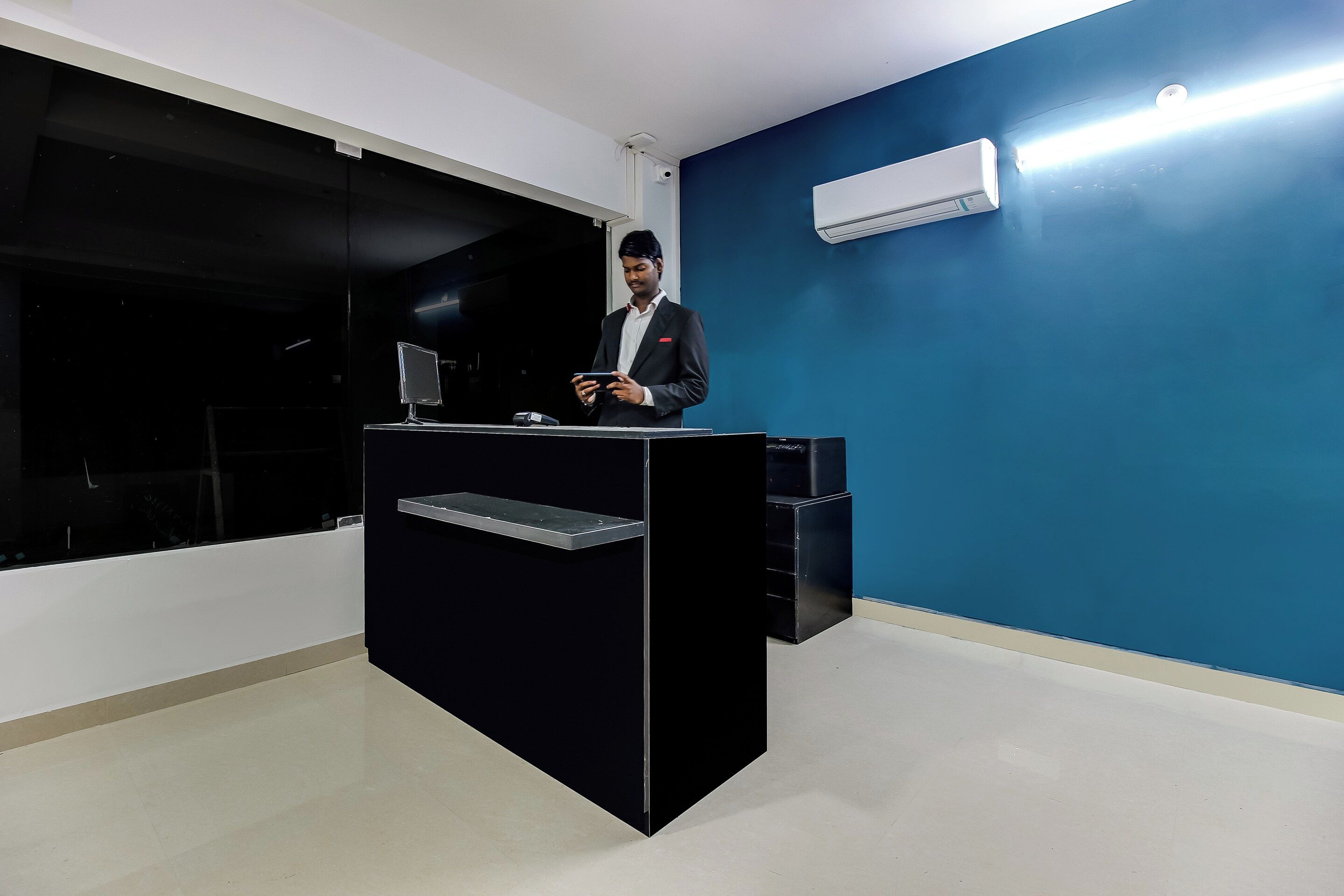 A reception desk with a computer monitor, a flat-screen TV, and a telephone.