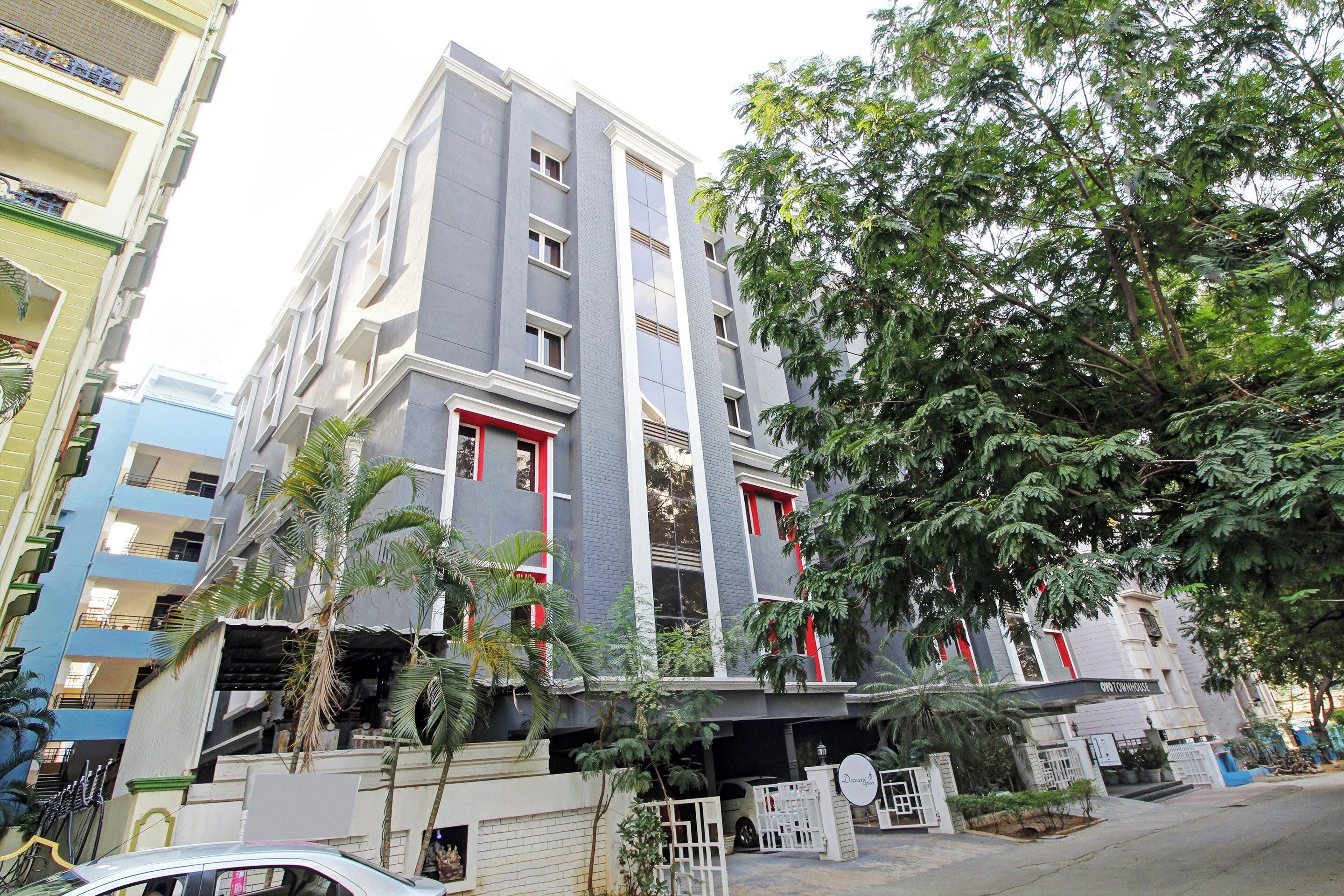 A multi-story residential building with balconies, a gated entrance, and surrounding greenery.