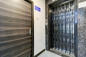 Puerta cerrada de ascensor con un letrero que indica '2do piso', una verja metálica con teclado numérico y una pared con un letrero que dice 'Bienvenidos a nuestro hotel'.