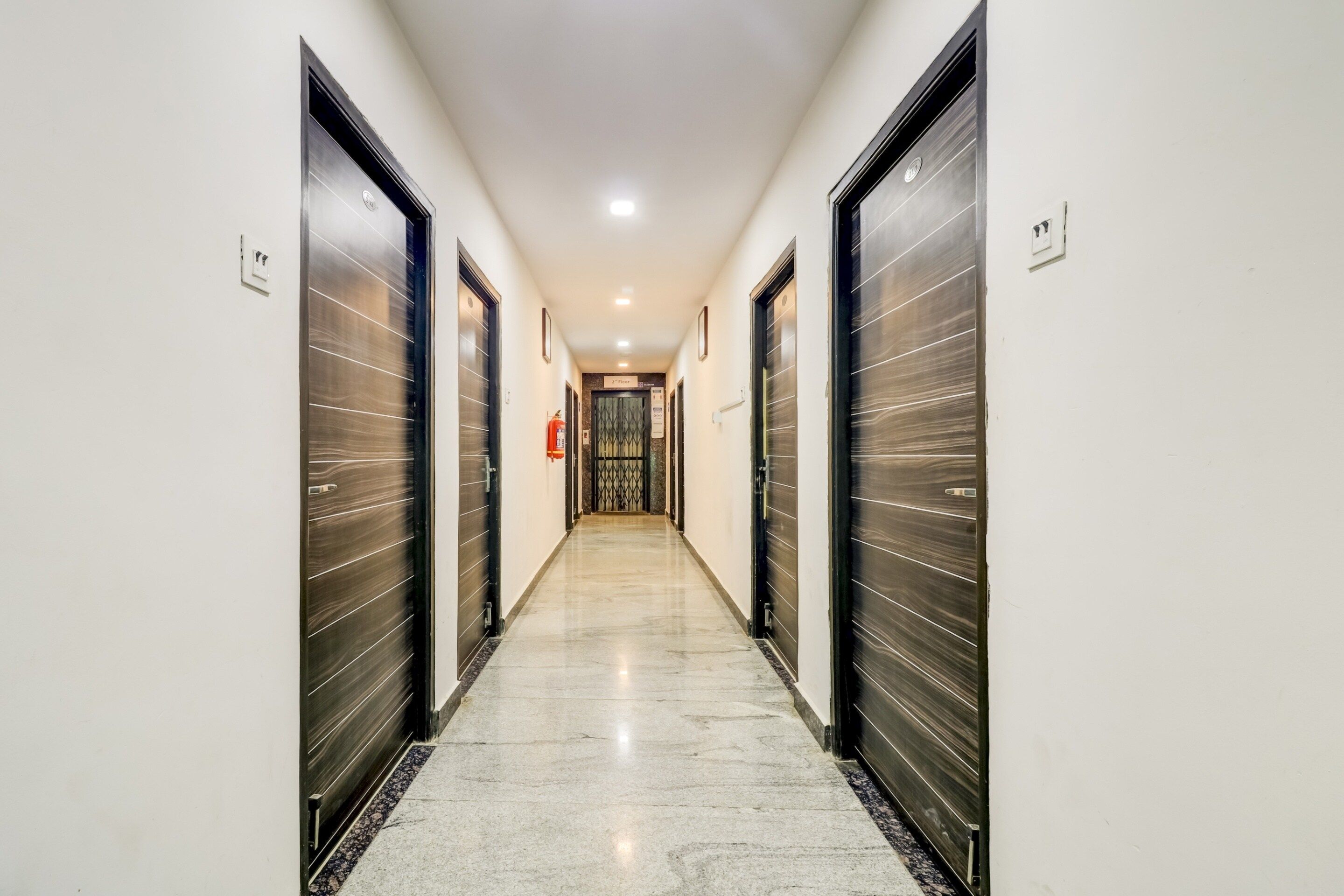 Un pasillo con puertas cerradas, un extintor y un letrero que indica el segundo piso.