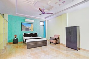 A bedroom with a bed, a chair, a wardrobe, a ceiling fan, and an air conditioning unit. - Hotel O Peaceful Stay Villa (Hyderabad)