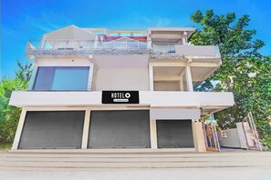 A hotel with a sign indicating it is company-serviced, featuring a modern design with multiple balconies and large windows. - Hotel O Peaceful Stay Villa (Hyderabad)