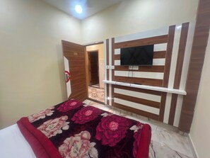 A hotel room with a bed, a TV mounted on the wall, and a door leading to another room. - Hotel O Citizen Residency (Amritsar)