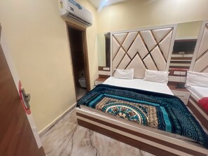 A hotel room with a bed, a bedside table, a mirror, and an air conditioning unit. - Hotel O Citizen Residency (Amritsar)