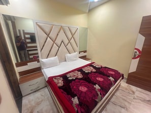 A bedroom with a bed, a dresser, a mirror, and a door with a circular sign. - Hotel O Citizen Residency (Amritsar)