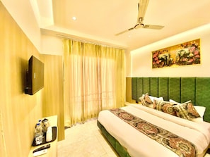 A hotel room with a bed, a flat-screen TV, a ceiling fan, and a painting on the wall. - Hotel O Park Plaza (Amritsar)