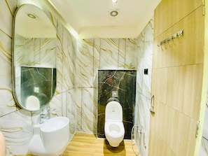 A modern bathroom with a marble wall, a white sink, a toilet, and a mirror. - Hotel O Park Plaza (Amritsar)