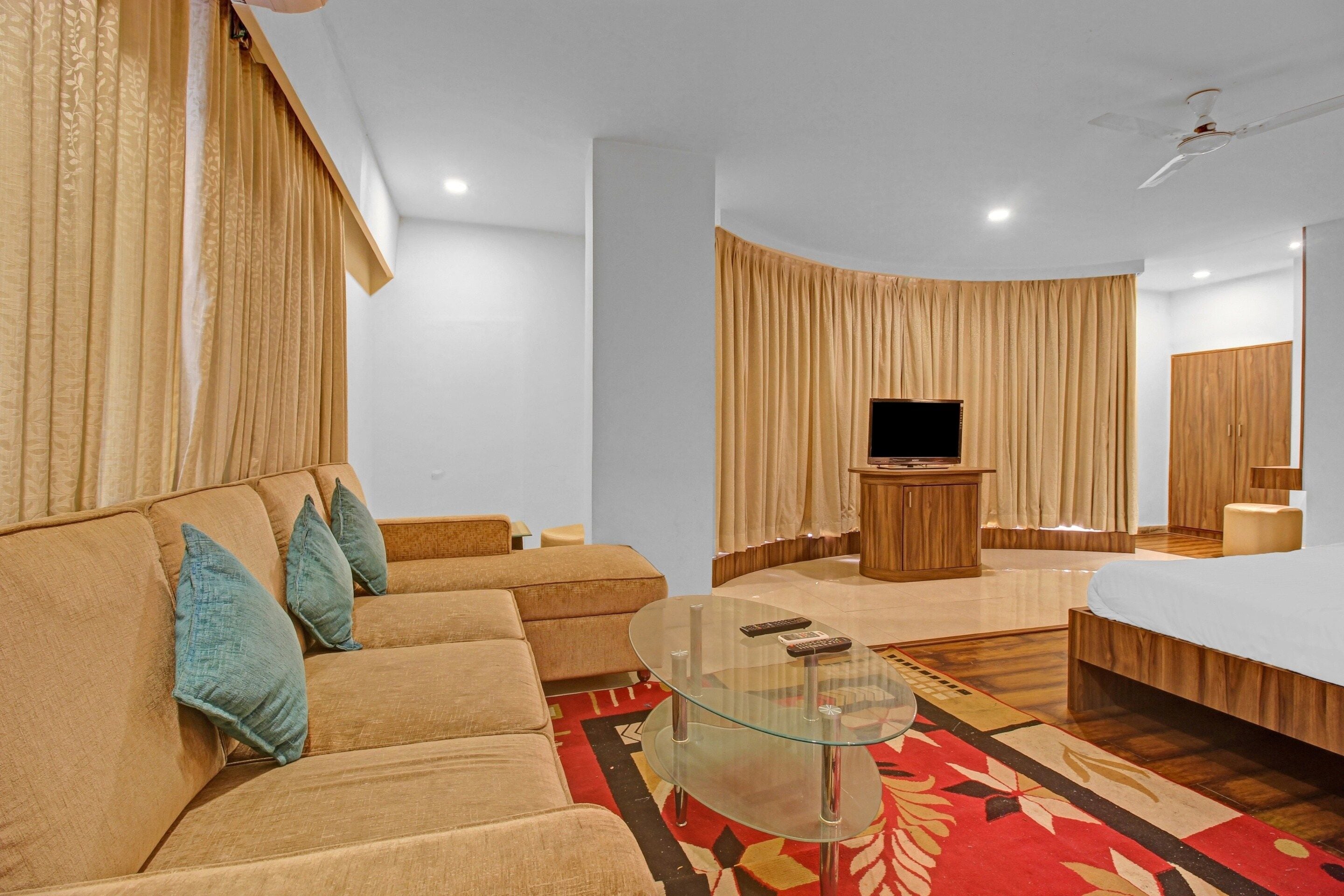 A modern living room with a sofa, a glass coffee table, a television, and a wooden cabinet.