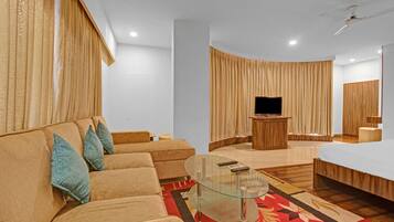 Una sala moderna con un sofá, una mesa de centro de vidrio, un televisor y un mueble de madera.