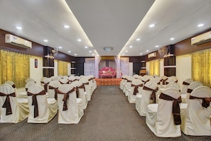 Un salón de conferencias con filas de sillas, un equipo de aire acondicionado y piso alfombrado.