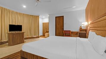 Habitación de hotel con una cama grande, televisor, escritorio con silla y armario.