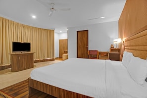 Habitación de hotel con una cama grande, televisor, escritorio con silla y armario.