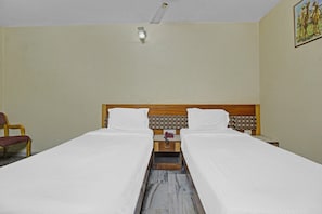A hotel room with two beds, a wooden headboard, a nightstand with a telephone, and a chair. - Hotel O Rahul International Hyderabad (Hyderabad)