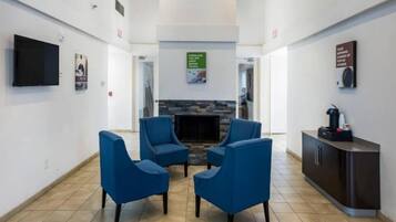 A reception area with a flat-screen TV, a fireplace, and a coffee machine.