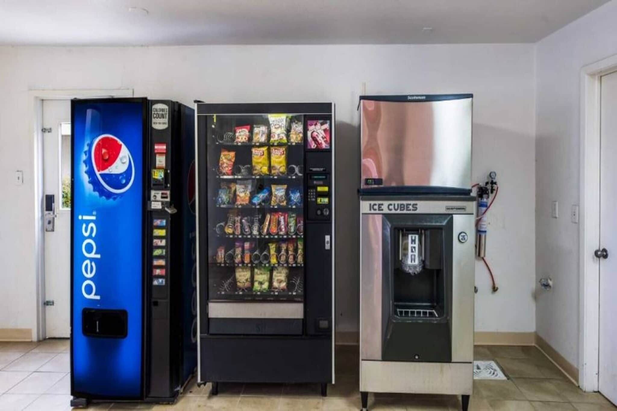 Tres máquinas expendedoras de bebidas en una habitación con paredes blancas y suelo de baldosas.