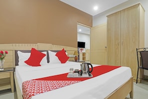 A hotel room with a bed, a nightstand, a TV, a wardrobe, and a coffee table with a kettle and cups. - Hotel O by OYO Padmini Near Lakdikapool (Hyderabad)