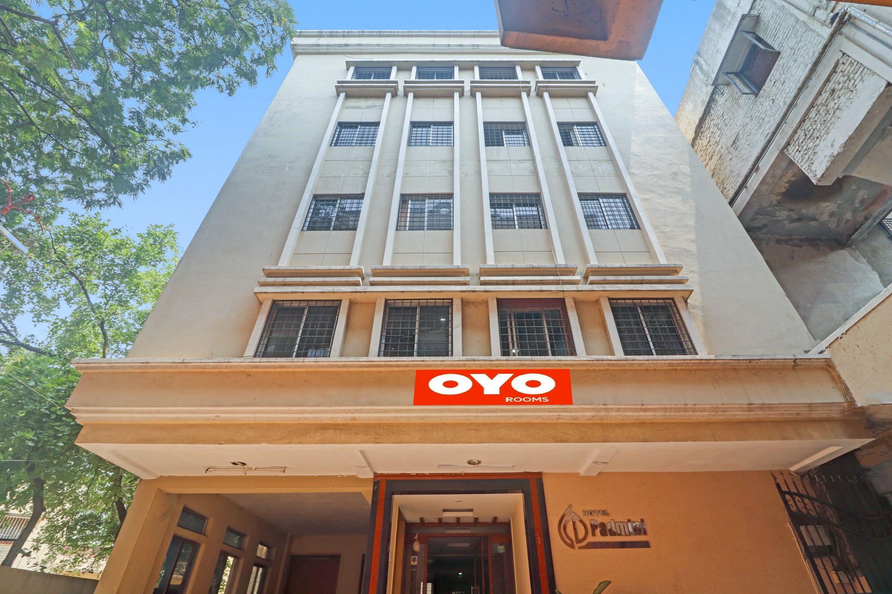 A hotel with a prominent 'OYO ROOMS' sign, a modern architectural design with vertical lines, and a clear entrance.