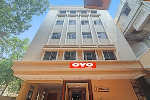 Un hotel amb un cartell ben visible de 'OYO ROOMS', un disseny arquitectònic modern amb línies verticals i una entrada clara.