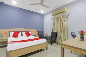 A hotel room with a bed, a desk, a chair, an air conditioner, and a ceiling fan. - Hotel O by OYO Padmini Near Lakdikapool (Hyderabad)