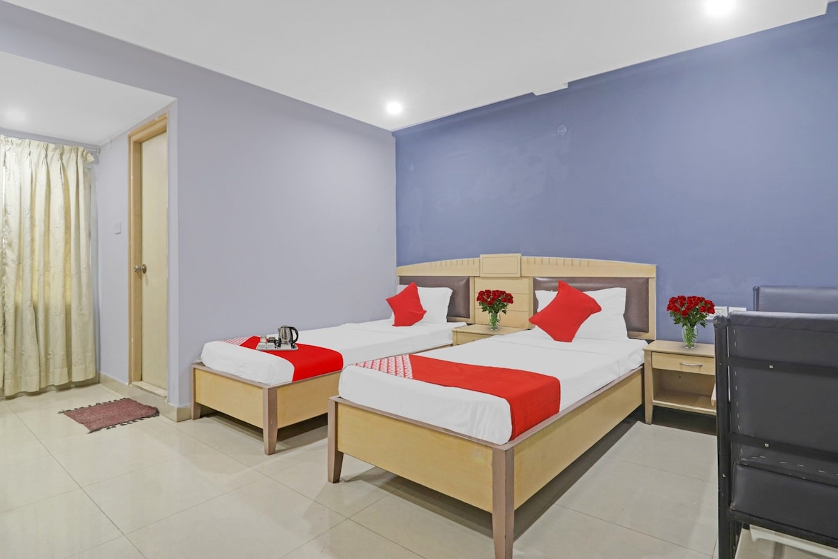 A hotel room with two beds, a desk, and a chair.