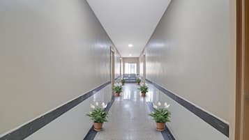 A corridor with a tiled floor, potted plants, and a door at the end.