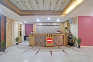 A reception area with a wooden reception desk, a clock, and a security camera. - Hotel O by OYO Padmini Near Lakdikapool (Hyderabad)