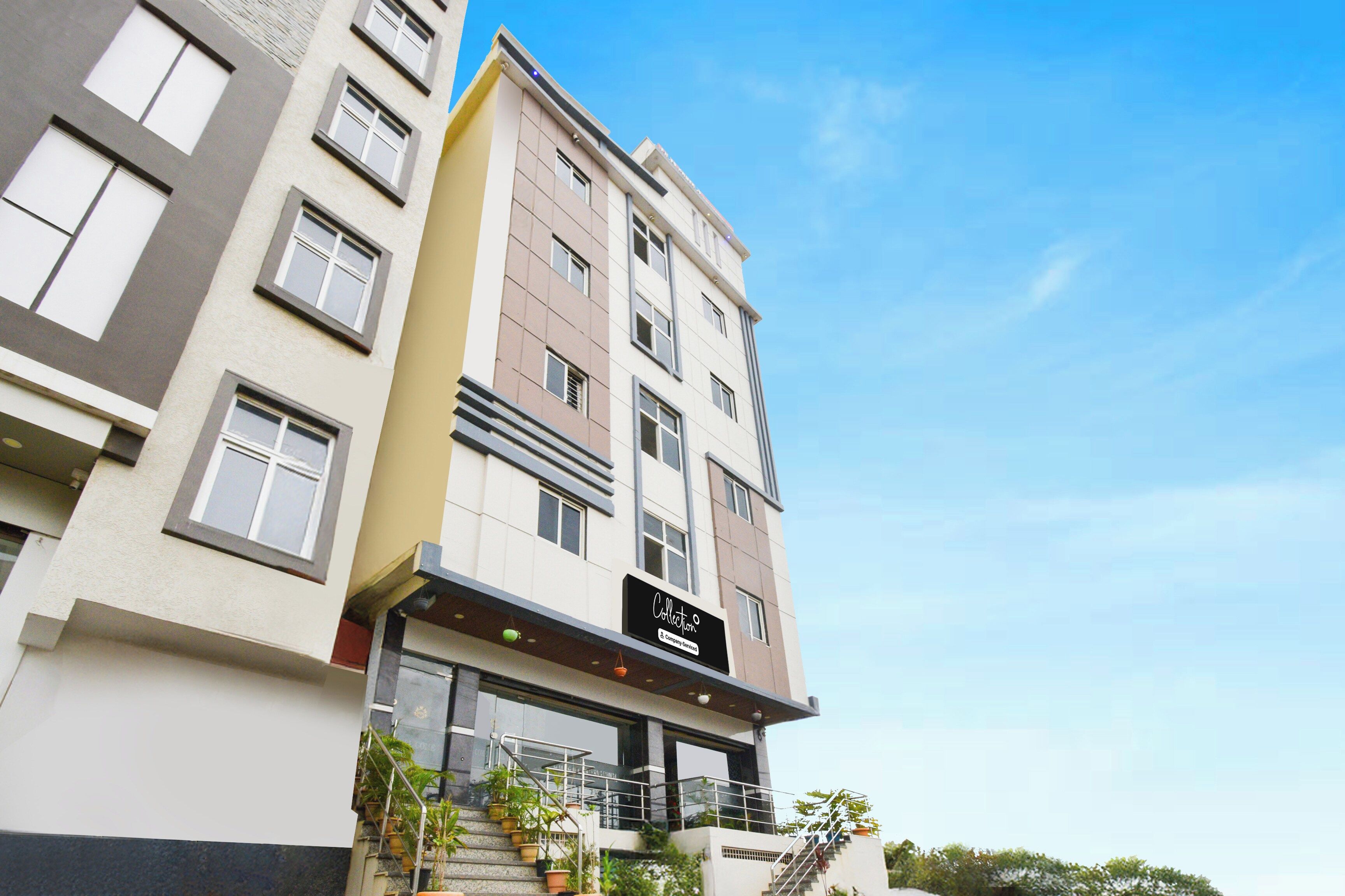 Hotel de vários andares com fachada moderna, escadaria visível e placa indicando serviço da empresa.