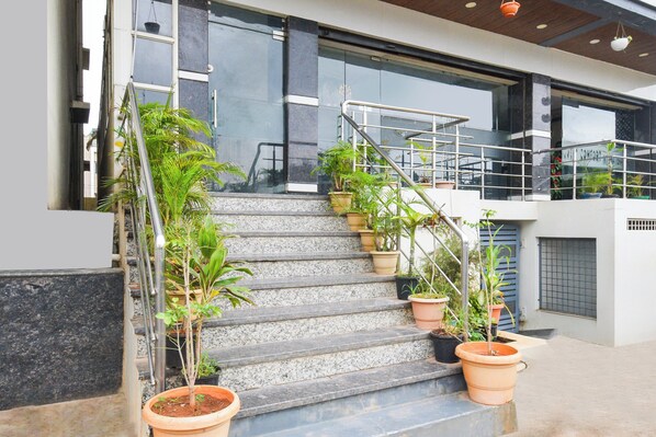 A staircase with multiple potted plants, a metal railing, and a modern building facade with large windows.