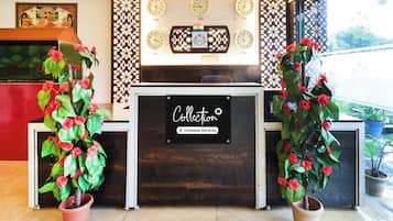 Un mostrador de recepción con un cartel que indica servicio de la empresa, rodeado de plantas decorativas y relojes mostrando diferentes husos horarios.
