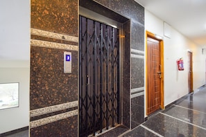 A hallway with a metal gate, a wooden door, and a fire extinguisher on the wall.