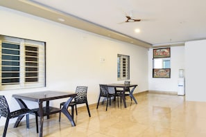 A spacious room with a dining table and chairs, a ceiling fan, and a water dispenser. - Hotel O Charminar international Hotel (Hyderabad)