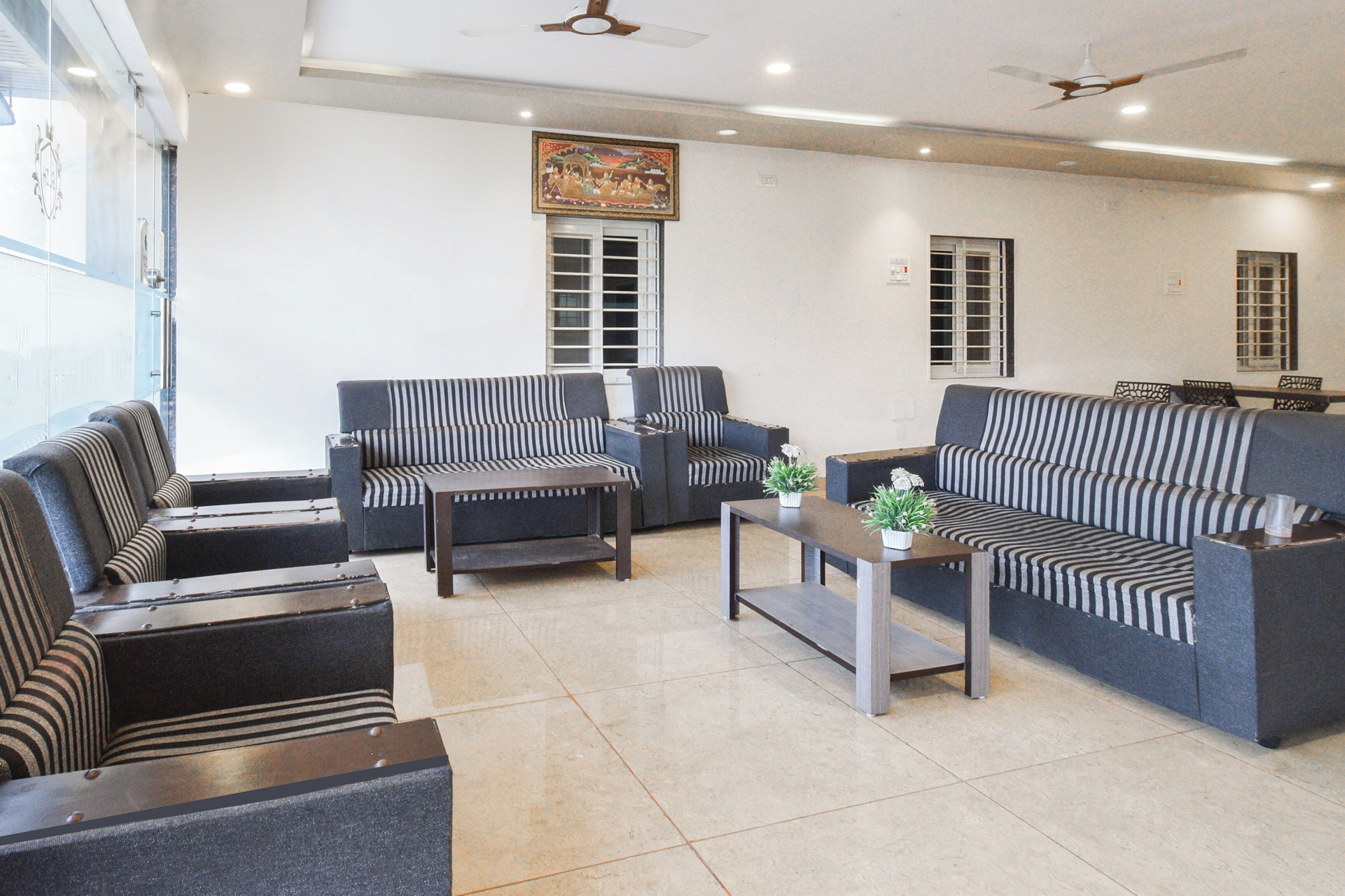 A modern lounge area with striped sofas, a coffee table, and ceiling fans.
