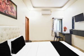 A hotel room with a bed, a desk, a chair, an air conditioning unit, a window with curtains, and a television. - Hotel O Charminar international Hotel (Hyderabad)